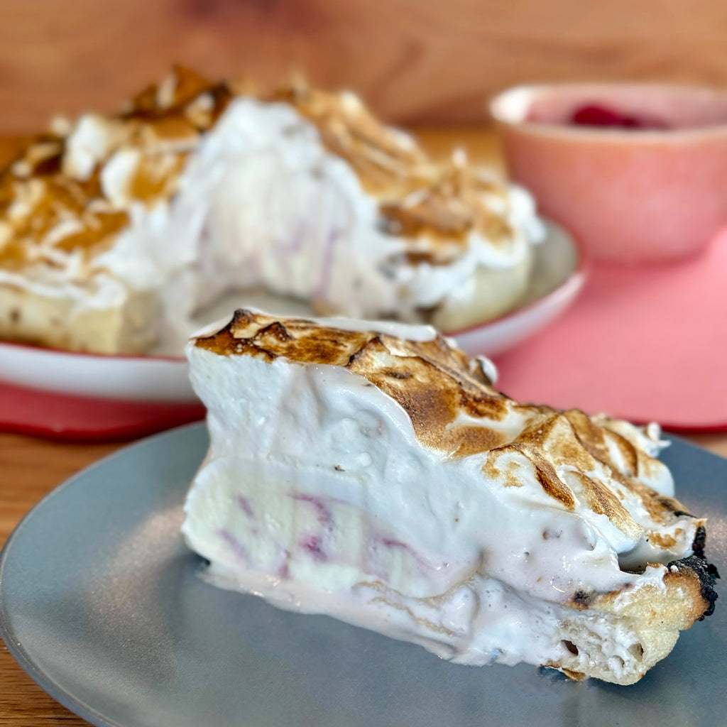 Slice of Baked Alaska pizza with fresh raspberries in the background