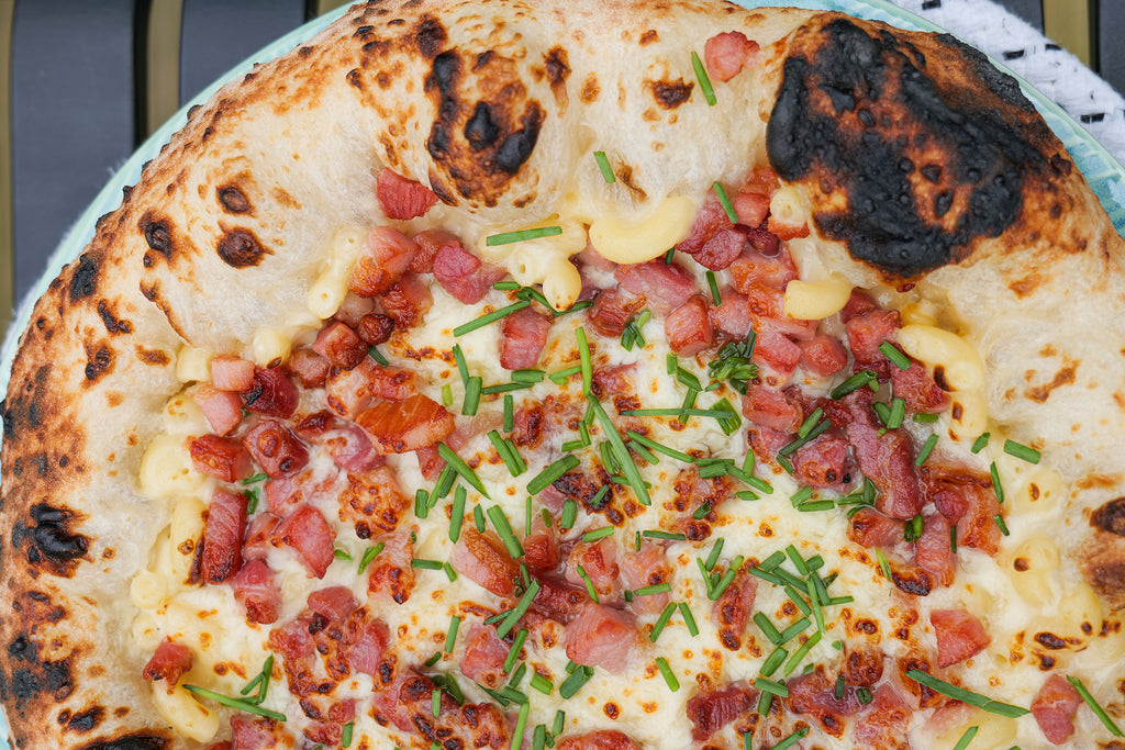 Macaroni cheese and pancetta on pizza, sprinkled with chopped chives