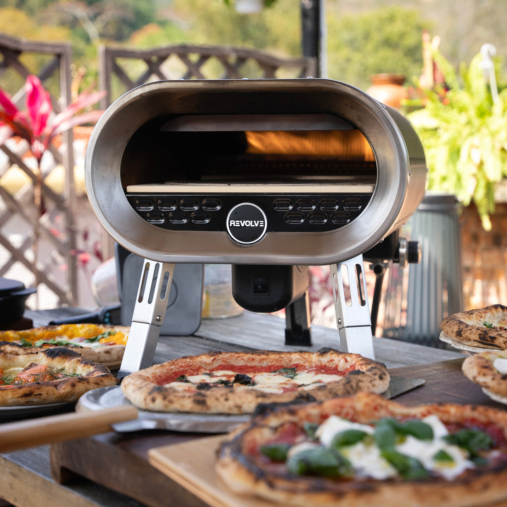 Revolve gas powered pizza oven in the garden, surrounded by pizzas