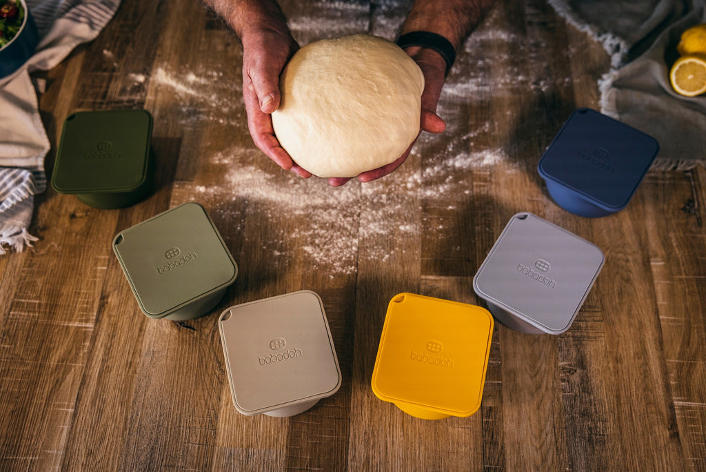 hands holding bulk proved pizza dough