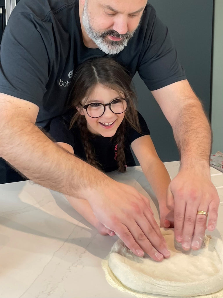 dad and daughter stretching out pizza dough