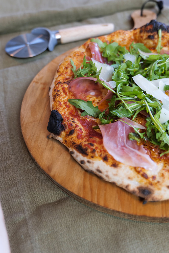 gluten-free pizza topped with prosciutto, rocket and parmesan cheese